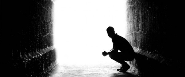 Human sitting silhouette in back-lit in tunnel exit